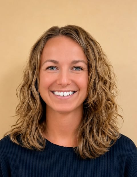 Smiling woman with long wavy reddish-brown hair wearing a black blazer against a white background