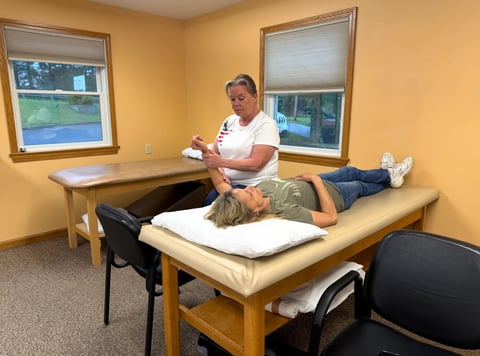 Physical therapist performing manual therapy on patient lying on treatment table in yellow medical office