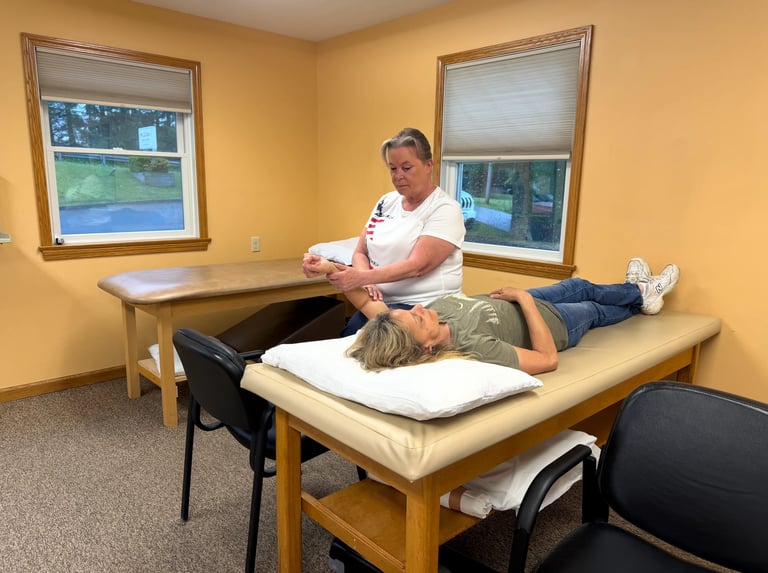 Physical therapist performing treatment on patient lying on examination table in clinic room with yellow walls