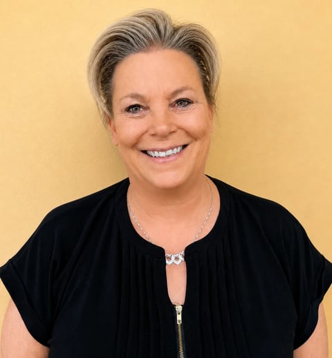 Professional headshot of a woman with blonde hair wearing a black blazer against a neutral background